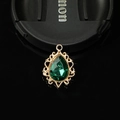 Macro view of a gold filigree teardrop pendant with a large green gemstone insert - Dark Green