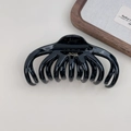 Detailed top view of a glossy black French-style octopus hair claw with branded lettering - Black