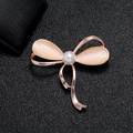 Elegant rose gold bow brooch featuring apricot cat eye stones and a white center pearl - Bowknot Opal