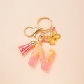 Detail of pink-yellow gradient letter N keychain with butterfly, tassel and golden clasp - Letter N