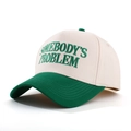 Detalle del bordado 'SOMEBODY'S PROBLEM' en una gorra de béisbol de dos colores - Beige/Verde Oscuro