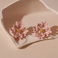 Macro detail of 3D pink flower stud earrings with golden pistil on artistic tray - Pink