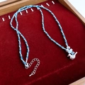 Detalle de collar de cordón tejido con colgante de pájaro plateado y cuenta azul - Plata-Azul