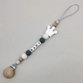 Detail of baby pacifier clip with beech wood, crown teether, and BABY letter beads - White
