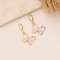Macro detail of 18K gold butterfly hoop earrings with iridescent opal-like wings and zircons - Yellow