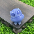 Carved blue natural stone owl figurine displayed on a wooden base with lawn background - Blue Luminous Stone