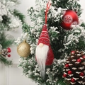 Detail of red knit gnome ornament hanging on snowy pine branch with festive decor - Style E