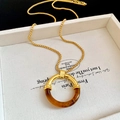 Détail macro du collier pendentif rond en résine rétro avec chaîne dorée brillante - Brun doré