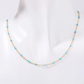 Bohemian gold chain necklace with turquoise enamel beads shown on a white mannequin - Blue