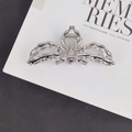 Top-down view of a large silver metal spider hair claw clip on a white magazine background - Exquisite Spider Hair Claw / Silver