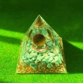 Orgone crystal pyramid with turquoise gravel, gold foil, and metal ring on green grass - 6cm / A32-Turquoise Metal Ring Dark Ball