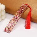 Macro shot of a clear acrylic bookmark with colorful sequins and a red silk tassel - Red