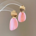Detail of gold wavy earrings with pink oval resin pendants on a transparent stand - Pink