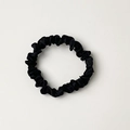 Glossy black satin scrunchie with silk texture and pleated design on light grey background - Black