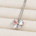 Silver butterfly necklace with rainbow zircons and white opal wings on a beige jewelry pad - Platinum