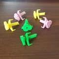 Portable plastic coconut opener tools in pink, yellow, and green on wooden background - Multicolor