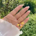 Dettaglio di una collana di perline in oro 18K con ciondoli a fiori e sfere in smalto - Set Estivo (Cappello da Sole/Ananas/Infradito)