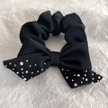 Detail of a black satin bow hair tie with sparkling rhinestone accents on white paper - Black
