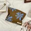 Makroansicht der Vintage-Kosmetiktasche mit blauen Blumenmustern und Webetikett - Braun
