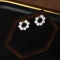 Floral circular freshwater pearl earrings with golden accents on a wooden display stand - Circular Pearl Stud Earrings