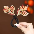 Détail d'un accessoire cheveux avec feuilles dorées, strass rouges et élastique noir - Feuilles Rouges