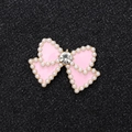 Pink bow jewelry charm with white pearls and central rhinestone on black background - Gold Base Pink Bow
