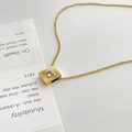 Dettaglio collana in titanio dorato con ciondolo quadrato a raggiera e pietra di zircone - Zircone Bianco Quadrato