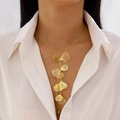 Dettaglio della collana con nappine a foglia di ginkgo dorata su camicia bianca - Collana con nappa a foglia di ginkgo oro