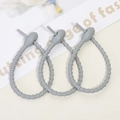 Three grey flexible silicone cable ties with adjustable holes for cable organization - Gray