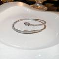 Detail of silver snake bracelet featuring pink diamond eyes on a white ceramic plate - Silver Snake Shape (8#)