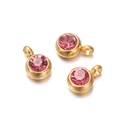 Macro detail of three gold-plated round pendants with pink faceted zircon stones - 10 Pieces per Pack / Gold Border Deep Pink Stone