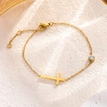 Dettaglio di un bracciale a catena dorata con ciondolo a croce e una pietra di zircone - Bracciale con Croce / Oro