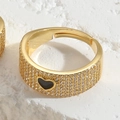 Vue macro d'une bague dorée 14K avec cœur noir et zircons sertis pour un éclat brillant - Noir