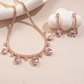 Detail of gold heart necklace and earrings set with pink zircon on white plate - Pink Heart Style