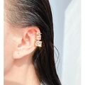 Golden ear cuff with three stepped square zircons worn on model's cartilage - Gold