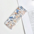 Macro shot of blue and orange marble-patterned cellulose acetate wide-tooth comb on book - Marble Pattern