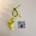 Macro shot of green fabric knot pendant with yellow carabiner and acrylic chain detail - Yellow-Green
