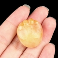 Natural yellow agate crystal carving in foot shape held in hand to show the actual size - Topaz