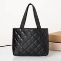Close-up detail of black quilted faux leather tote bag with woven handles and diamond pattern - Horizontal / Black