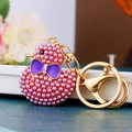 Macro shot of pink pearl-inlaid duck keychain with purple bow and golden lobster clasp - Purple Pearl Duck