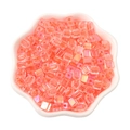Vibrant orange iridescent cube beads in a white floral dish for DIY jewelry making - Orange