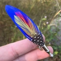 Gros plan détaillé d'une broche en plumes de paon aux textures bleu et rouge vif - Dégradé Bleu Rouge Jaune (Style 1)