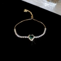 Detail of a gold heart-shaped bracelet with green zircon and adjustable slider clasp - Gold - Green Zirconia