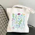 Minimalist white wildflower garden canvas tote bag shown on a mesh metal chair - C4 Vibrant Mixed Flower Illustration