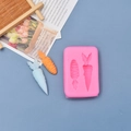 Detail of pink silicone mold with carrot cavities and finished fondant carrot samples - Carrot