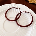 Dettaglio di orecchini a cerchio smaltati bordeaux su un piatto decorativo in ceramica bianca - Rosso Scuro