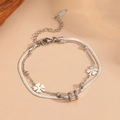 Detailed macro view of silver stainless steel double-layer clover bracelet on beige paper - T408 Steel Bracelet