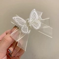 Fermaglio a farfalla in rete bianca con tre perle eleganti su sfondo crema delicato - Bianco