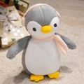 Dettaglio di un peluche a forma di pinguino con sciarpa rosa e paraorecchie in scena festiva - Pinguino Grigio