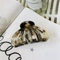 Gros plan d'une pince à cheveux en acétate écaille de tortue avec texture ambrée - Environ 9 cm / Marbre à l'Encre